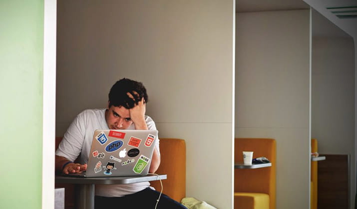 male on laptop with hand in hair